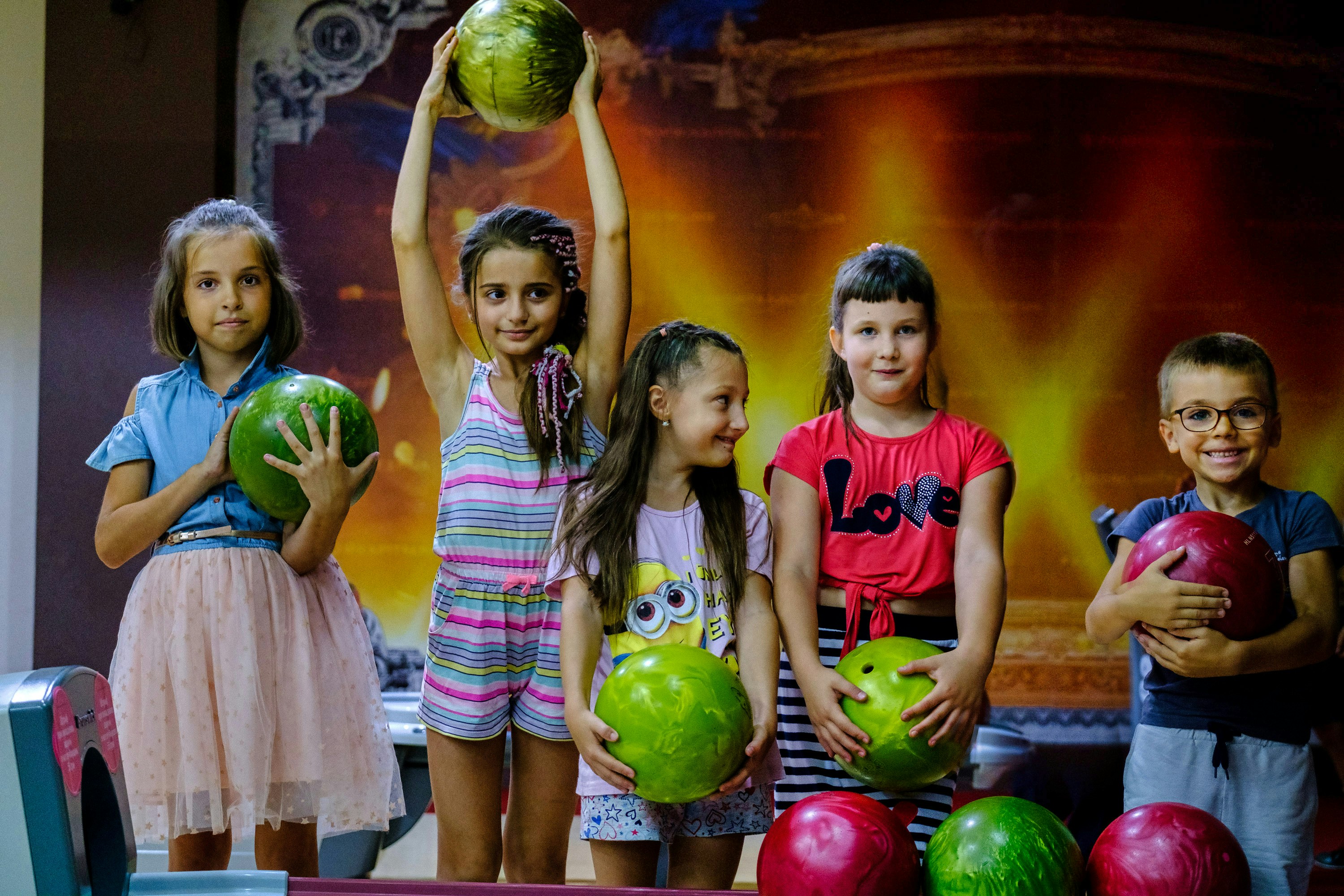 Kids holding bowling balls at a birthday party